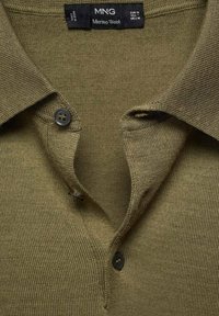 Olive green merino wool polo shirt with a textured knit, featuring a folded collar and two black buttons at the placket.
