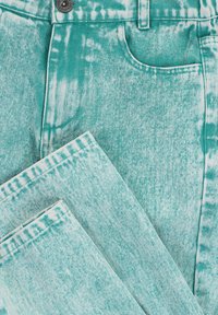 Turquoise denim jeans met een vervaagd, acid-wash patroon. Kenmerken zijn een voorzak en een metalen knoop boven de rits.