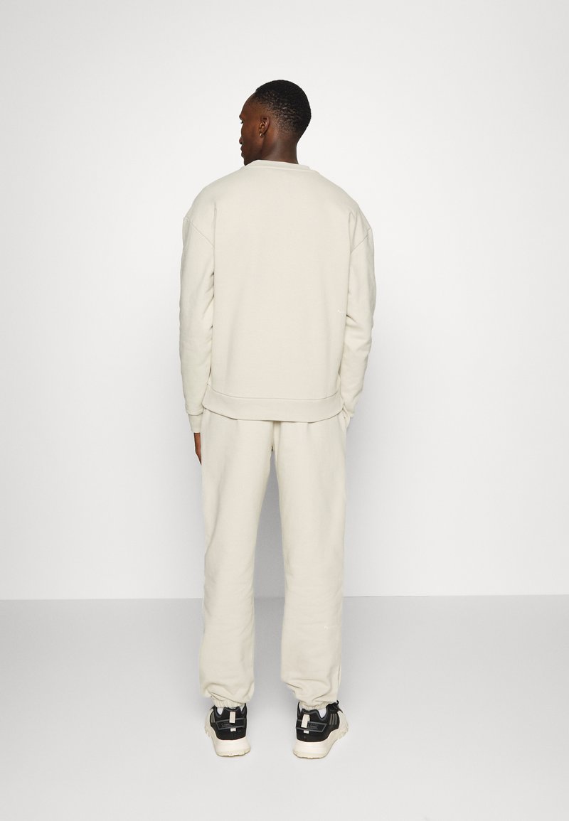 Herren Trainingsanzüge | pinqponq UNISEX Jogginghose cliff beige/beige - LS51181 Herren Trainingsanzüge | pinqponq UNISEX Jogginghose cliff beige/beige - LS51181