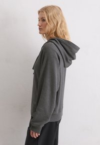 Felpa con cappuccio grigia realizzata in tessuto morbido, con tasca a marsupio e polsini a costine, dal taglio rilassato e dettagli di design semplici.