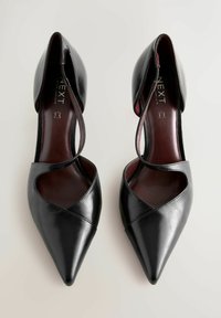Pantofi din piele neagră, cu vârful ascuțit și decupaje în cruce, cu un design elegant. Finisaj neted cu o textură lucioasă. Părți laterale deschise, fără accesorii.