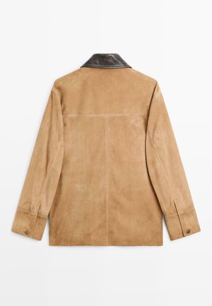 Veste en daim beige clair avec un col en cuir noir. Elle présente des manches longues et des détails de couture subtils. Texture lisse.