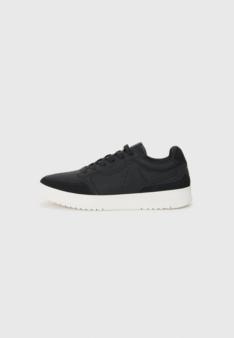 Black athletic shoe featuring smooth synthetic upper, textured accents, lace closure, and a white rubber sole with a patterned tread.