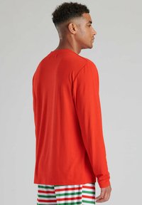 Camisa de manga larga de algodón rojo brillante, con cuello redondo y corte relajado. La vista trasera muestra una textura suave sin patrones.