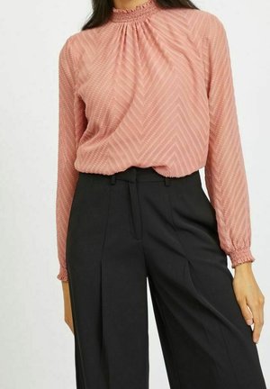 Różowa bluzka z długim rękawem z wysokim marszczonym kołnierzem, ozdobiona wzorem jodełki i luźnym krojem, w połączeniu z czarnymi, dopasowanymi spodniami.