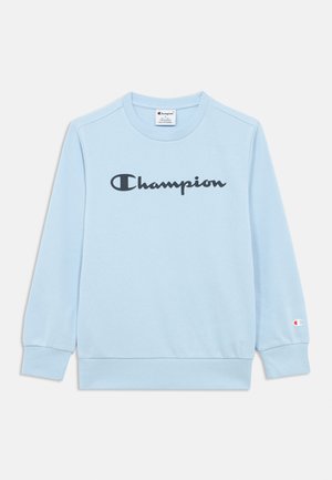 Hele sinine pika varrukaga dressipluus, millel on must "Champion" logo rinna keskosas ja väike Champion logo vasaku varruka mansetil.