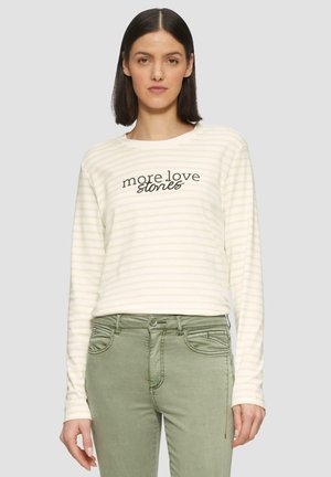 Licht gestreepte langemouwen shirt met zwarte tekst "more love stories" op de voorkant. Gecombineerd met groene stoffen broeken met zakdetails.
