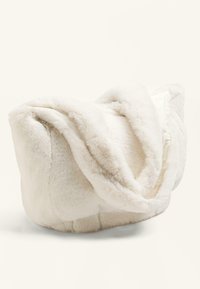 Meka od mekog bijelog umjetnog krzna s plišastom teksturom, okruglim oblikom i drapiranim dizajnom. Tkanina ima sjaj koji dodatno pojačava njen udoban izgled.