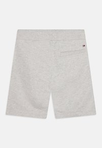 Pantaloni corti in cotone grigio chiaro con cintura piatta, tasca posteriore e accento del logo vicino alla tasca. Texture liscia e vestibilità standard.