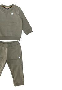 Felpa verde oliva per toddler con pantaloni abbinati, cinturini a coste, piccolo logo bianco sul petto e sulla coscia, disposti su uno sfondo bianco.