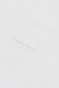 Primer plano de tela blanca con el sutil logo de la marca "intimissimi" bordado, visible en la superficie suave del textil.