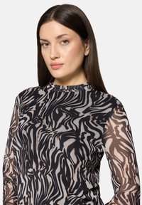 Przezroczysta czarno-beżowa bluzka z długim rękawem, z wirującym abstrakcyjnym wzorem, wysokim kołnierzem i lekkim, fakturowanym materiałem.