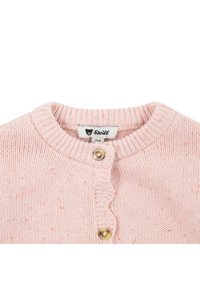 Svetle růžový pletený cardigan s ribovaným límcem, dvěma zlatými knoflíky a vlnitým okrajem podél knoflíkové légy. Viditelná značka Steiff.