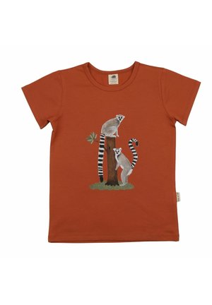 Rust-colored short-sleeve shirt with a design of two ring-tailed lemurs on a tree stump with green grass and a small branch.