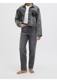 Grå denimjacka med en kortad design, knäppning med knappar och en ficka med patch. Kombinerad med högmidjade grå jeans, båda med en texturerad yta.