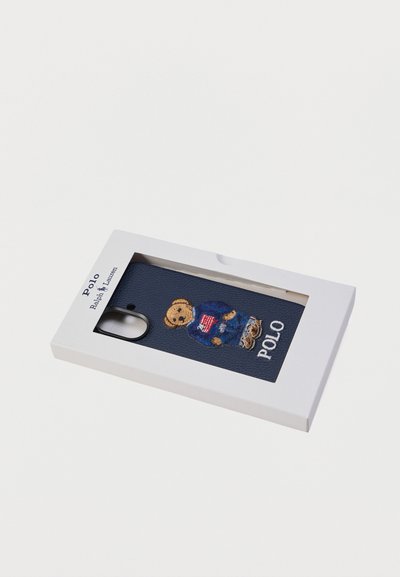 Θήκη τηλεφώνου από ναυτικό δέρμα με κεντημένη αρκουδάκι με πουλόβερ και το κείμενο "Polo", παρουσιασμένη σε λευκό κουτί.
