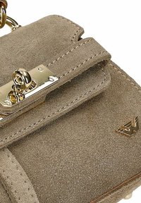 Petit sac à main en daim beige avec fermoir à tour doré et logo ailé doré dans le coin inférieur droit.
