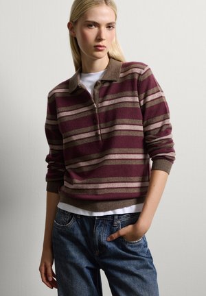 Maglione a righe bordeaux e beige in maglia con colletto a polo, dotato di patta con bottoni e polsini a coste, abbinato a jeans in denim blu.