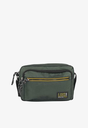 Bolsa de lona verde con dos bolsillos con cremallera, ribete negro y acento amarillo. Cuenta con correa ajustable y parche con logo. Superficie texturizada.