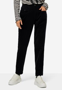 Marineblauwe corduroy broek met een rechte pijp, voorzien van voorzakken en een knoopsluiting, gecombineerd met witte sneakers en een gestreept shirt.
