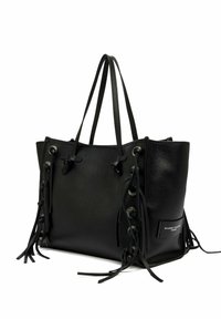Sac fourre-tout en cuir noir avec double anses, détails à lacets sur le côté avec des franges, et un petit patch logo blanc sur le panneau latéral.
