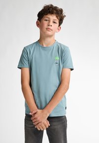 Camiseta de algodón de color azul claro con cuello redondo y mangas cortas. Bordada con un diseño de palmera en el lado izquierdo del pecho. Se ajusta perfectamente al cuerpo.