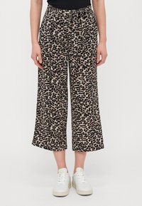 Bredde leggbukser med leopardmønster, med strikk i midjen, myk stoff og overveiende beige med svarte detaljer.