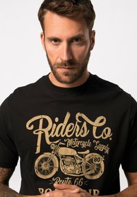 Sort t-shirt med en vintage motorcykelgrafik i beige, med slidt skrift, rund halsudskæring og korte ærmer.