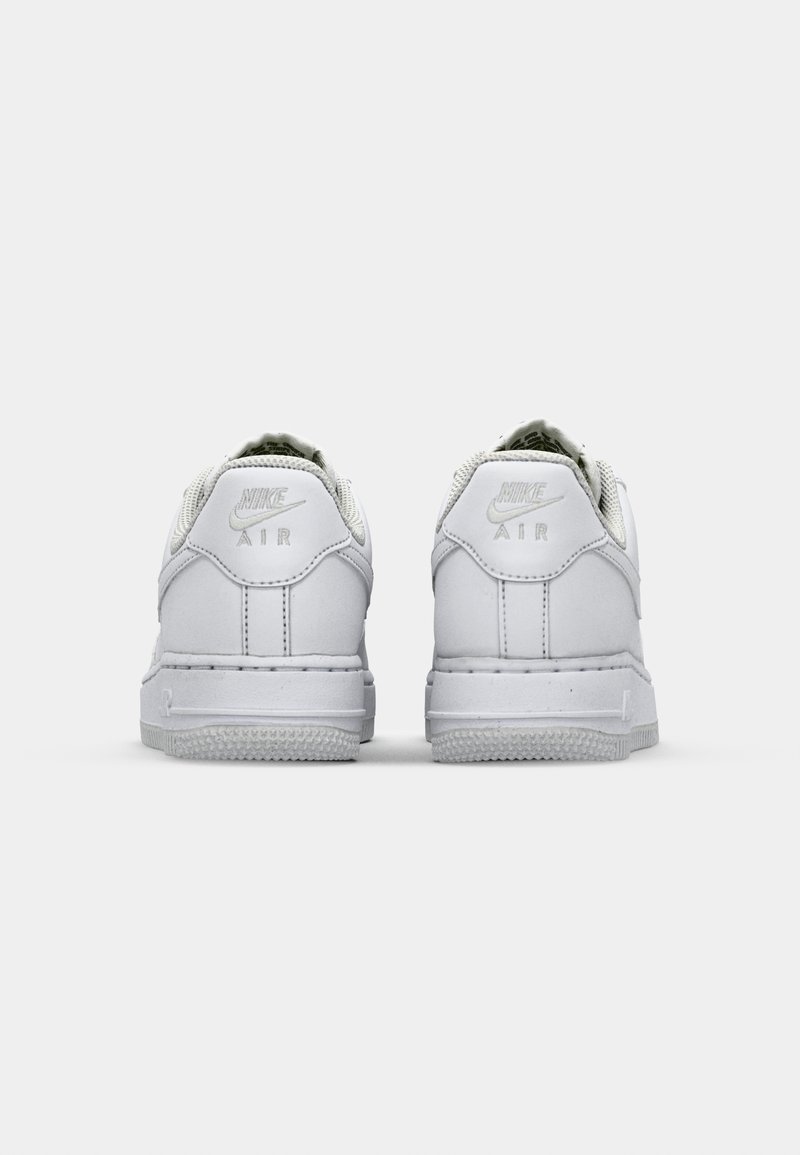 Des baskets Nike Air blanches présentent une tige en cuir lisse, un talon texturé et un col rembourré. Comprend un logo en relief et une semelle en caoutchouc.
