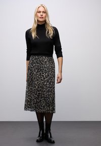 Černý rolák, midi sukně s leopardím potiskem, průhledná textura, délka po kotníky, nošena s černými koženými botami na šedé podlaze.