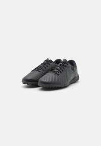 Black athletic shoes with a textured synthetic upper, lace-up design, and rubber outsole featuring small studs for traction.