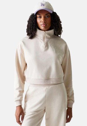 Beige cropped sweatshirt met een hoge kraag en kwart-ritssluiting, met geborduurde logo-details. Zachte, textuurrijke stof met geribde manchetten.
