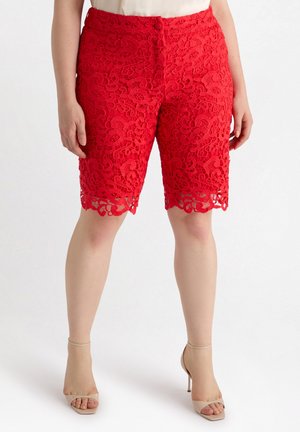 Bermudas de encaje rojo con un patrón floral, con un dobladillo con forma de ondas y cierre de botón en la cintura. Textura suave.