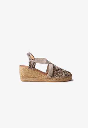 Kiil-kanna espadrillide king, mille ülaosa on kaetud sebra mustriga kangaga, beežide ristsangadega ja punutud juta platvormpõhjaga.