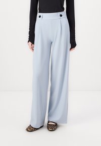 Světle modré kalhoty s širokými nohavicemi a plisováním, s vysokým pasem a dvěma černými knoflíky. Hladký materiál, v kombinaci s tištěnými balerínami.