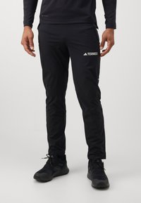 Black athletic pants made of lightweight, moisture-wicking material. Features a slim fit, elastic waistband, and contrasting white branding.