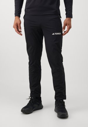 Zwarte sportieve broek van lichtgewicht, vochtafvoerende stof. Kenmerkt zich door een slim fit, elastische tailleband en contrasterende witte branding.