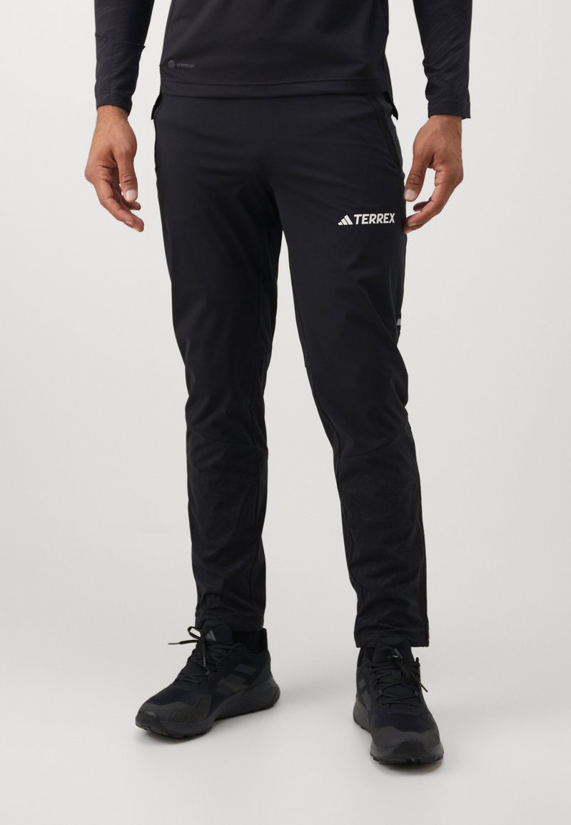 Black athletic pants made of lightweight, moisture-wicking material. Features a slim fit, elastic waistband, and contrasting white branding.