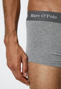 Boxer shorts in cotone grigio con una vita grigia etichettata "Marc O'Polo." Il tessuto sembra morbido con una texture liscia, design aderente.