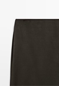 Tissu brun foncé texturé avec de subtiles lignes verticales, présenté à plat sur un fond blanc, mettant en valeur le détail du matériau.