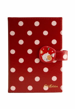 Red wallet with white polka dots, a clasp featuring a cat face and apple design, and gold "Cath Kidston" logo in the bottom right corner.