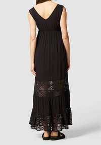 Mustapitu maxi-mekko V-back -leikkauksella, jossa on teksturoitu bodice, kerroksellinen pitsihame ja aallotettu helma. Pehmeää ja virtaavaa kangasta.