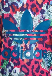 Tejido colorido con un fondo de estampado de leopardo y acentos florales. Un gran logo azul de Adidas se muestra de manera prominente, texturizado y audaz.