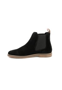 Stivale Chelsea in suede nero con pannelli elastici laterali, punta arrotondata e un piccolo tacco beige. Presenta un tassello sul retro per una facile calzata.