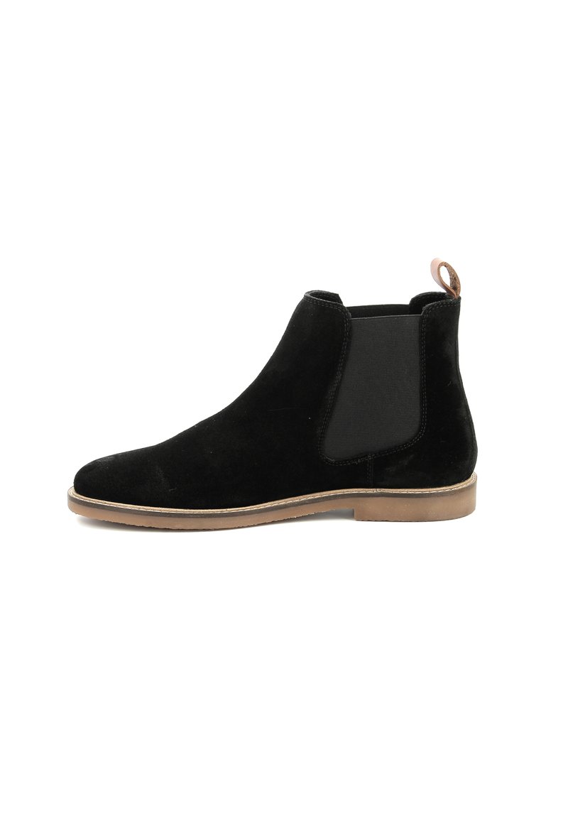 Stivale Chelsea in suede nero con pannelli elastici laterali, punta arrotondata e un piccolo tacco beige. Presenta un tassello sul retro per una facile calzata.
