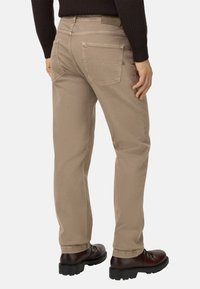 Pantalones de algodón color beige con un corte recto, dos bolsillos traseros y una etiqueta de marca visible en la cinturilla. Textura de tejido duradero.