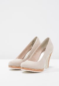 Beige suede high heels with a round toe, cork platform, and white heel. Smooth texture and minimalistic design.