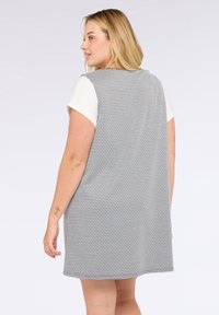 Schwarzes und weißes Hahnentritt-Kleid mit lockerer Passform, ärmellosem Design und strukturiertem Stoff. Verfügt über einen runden Ausschnitt und eine Länge über dem Knie.