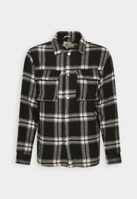 Sort-hvid ternet flannel skjorte med lange ærmer, knaplukning, to forlommer og klassisk krave. Blød tekstur.