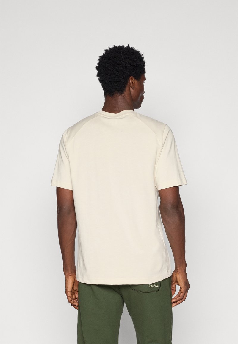 Cremefarbiges T-Shirt mit kurzen Ärmeln und runder Ausschnitt, das eine glatte Textur und kontrastierende Nähte an den Raglanärmeln aufweist.